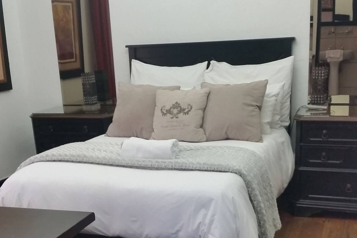 A bedroom with a bed, nightstands, a dresser, and a mirror.