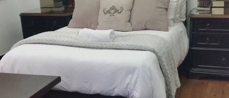 A bedroom with a bed, nightstands, a dresser, and a mirror.