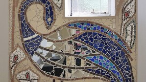A mosaic wall with a curved design, a window, and a door. - Izimbali Lodge (Ermelo)