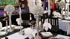 A restaurant interior with tables set for dining, featuring silverware, plates, and glassware. - Izimbali Lodge (Ermelo)
