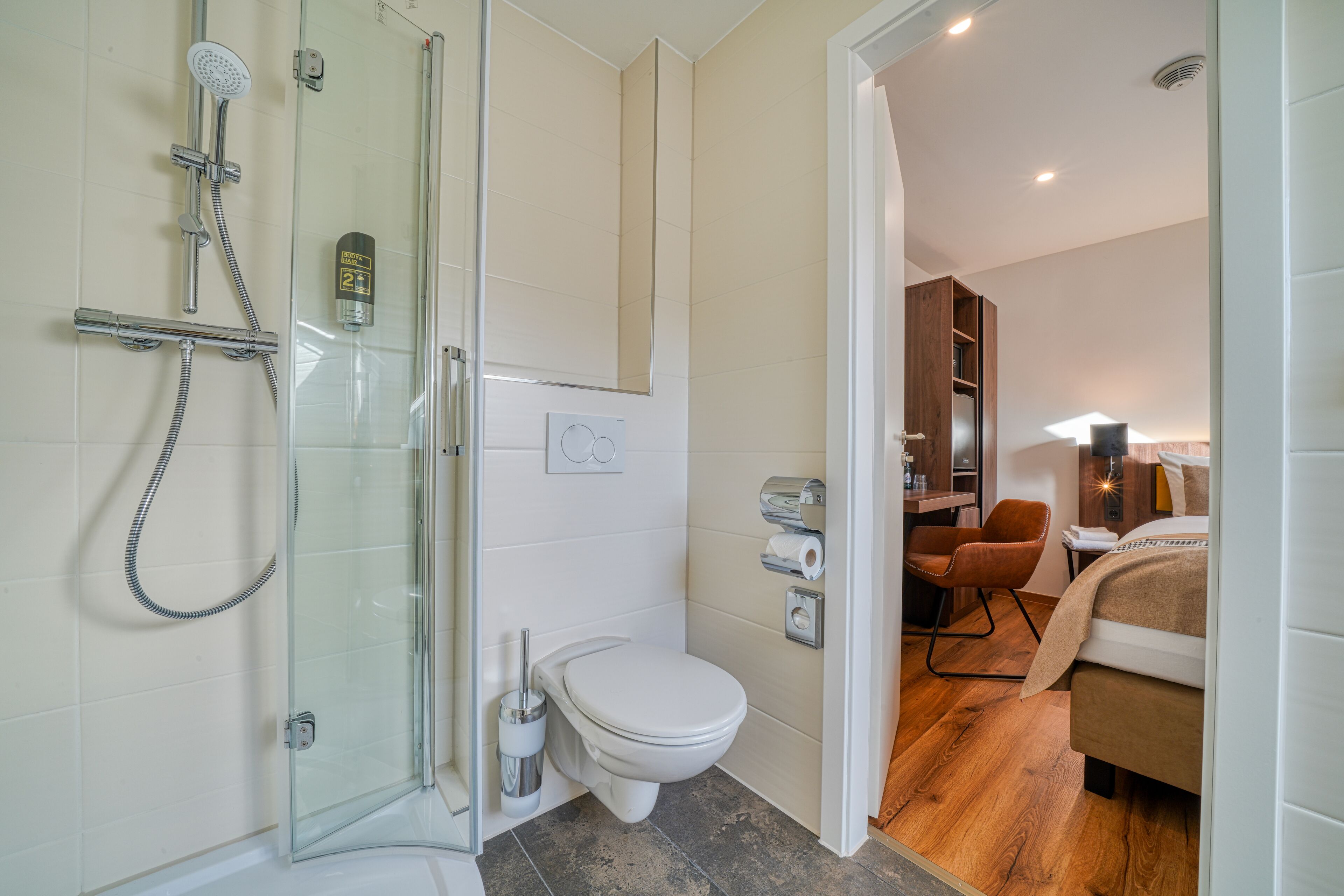 A modern bathroom with a glass shower enclosure, a toilet, and a sink.