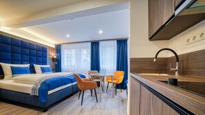Une chambre d’hôtel moderne dotée d’un grand lit, d’un coin repas et d’une cuisine.