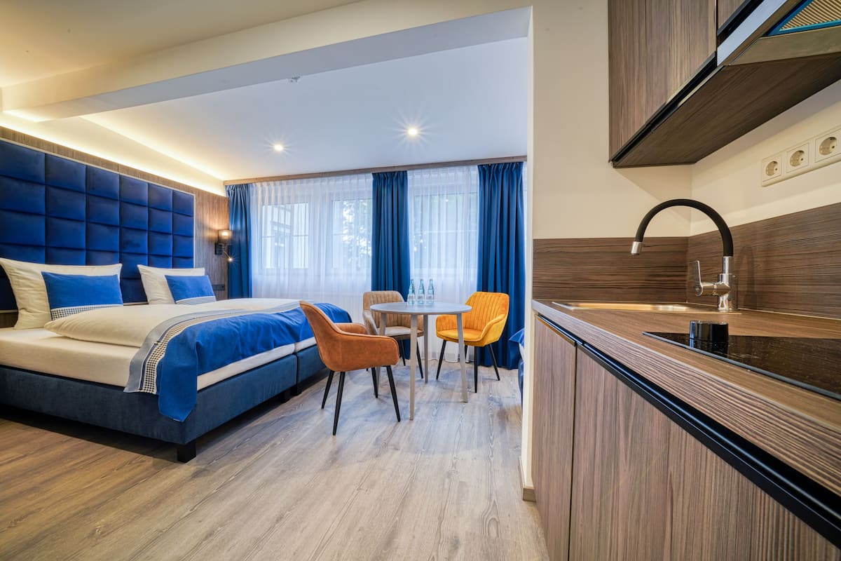 Una habitación de hotel moderna con una cama grande, un comedor y una cocina.