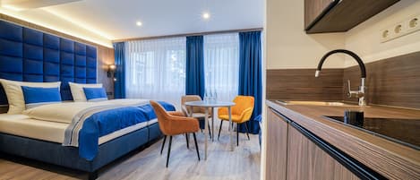 Una habitación de hotel moderna con una cama grande, un comedor y una cocina.