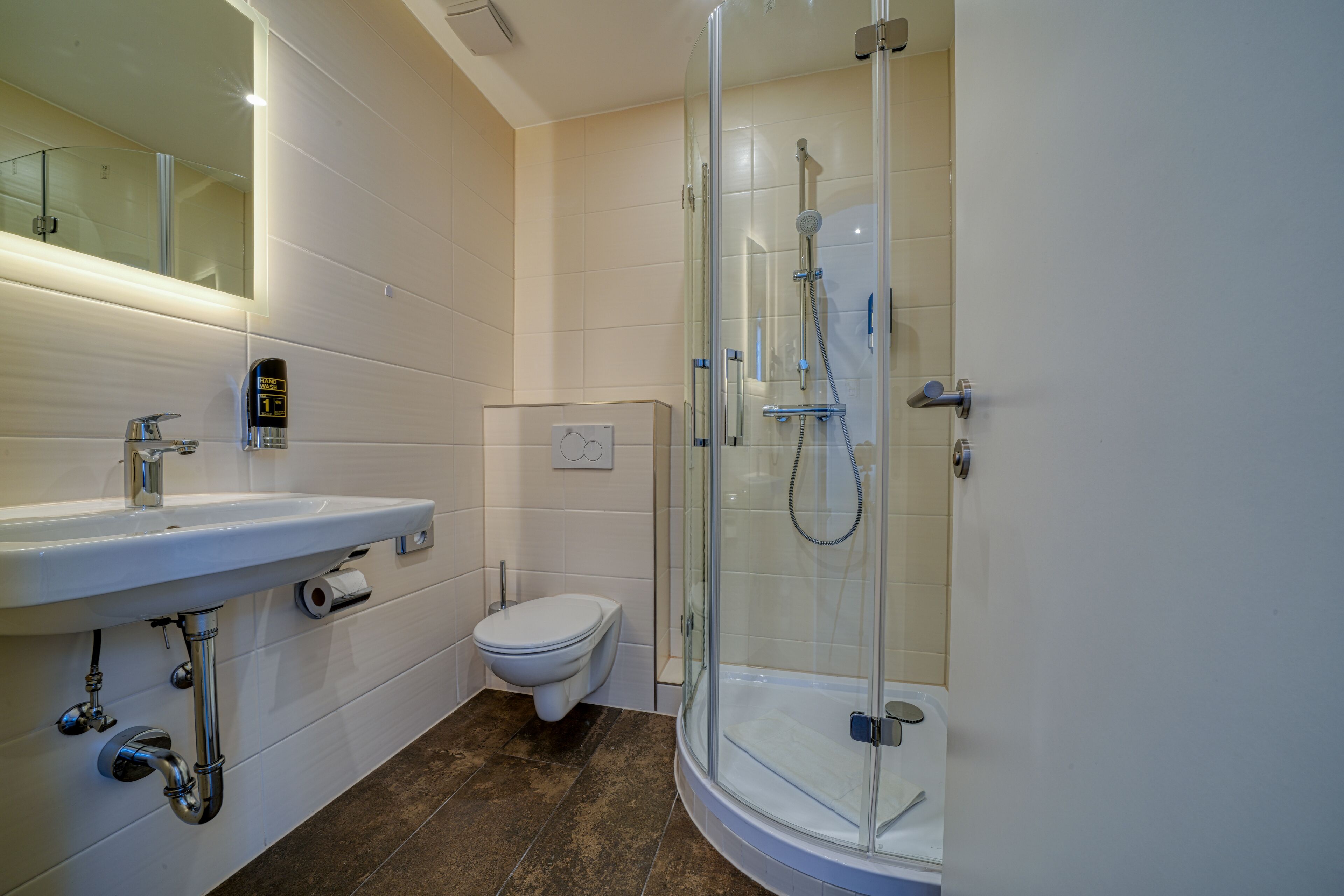 A modern bathroom with a glass-enclosed shower, a white sink, and a toilet.