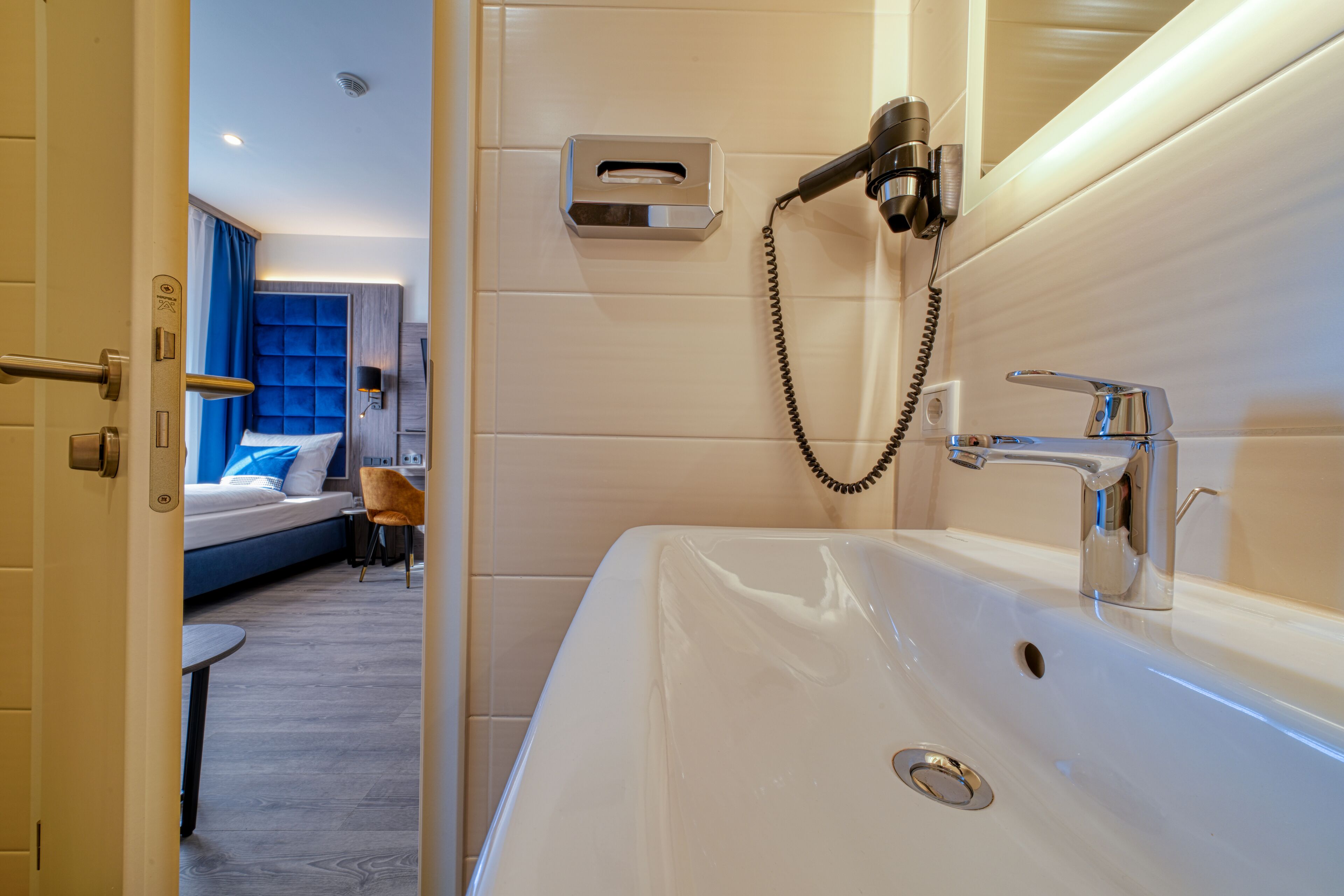Ein modernes Badezimmer mit einem großen, weißen Waschbecken, einer Handbrause und einem Handtuchspender.