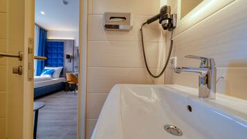 Ein modernes Badezimmer mit einem großen, weißen Waschbecken, einer Handbrause und einem Handtuchspender.