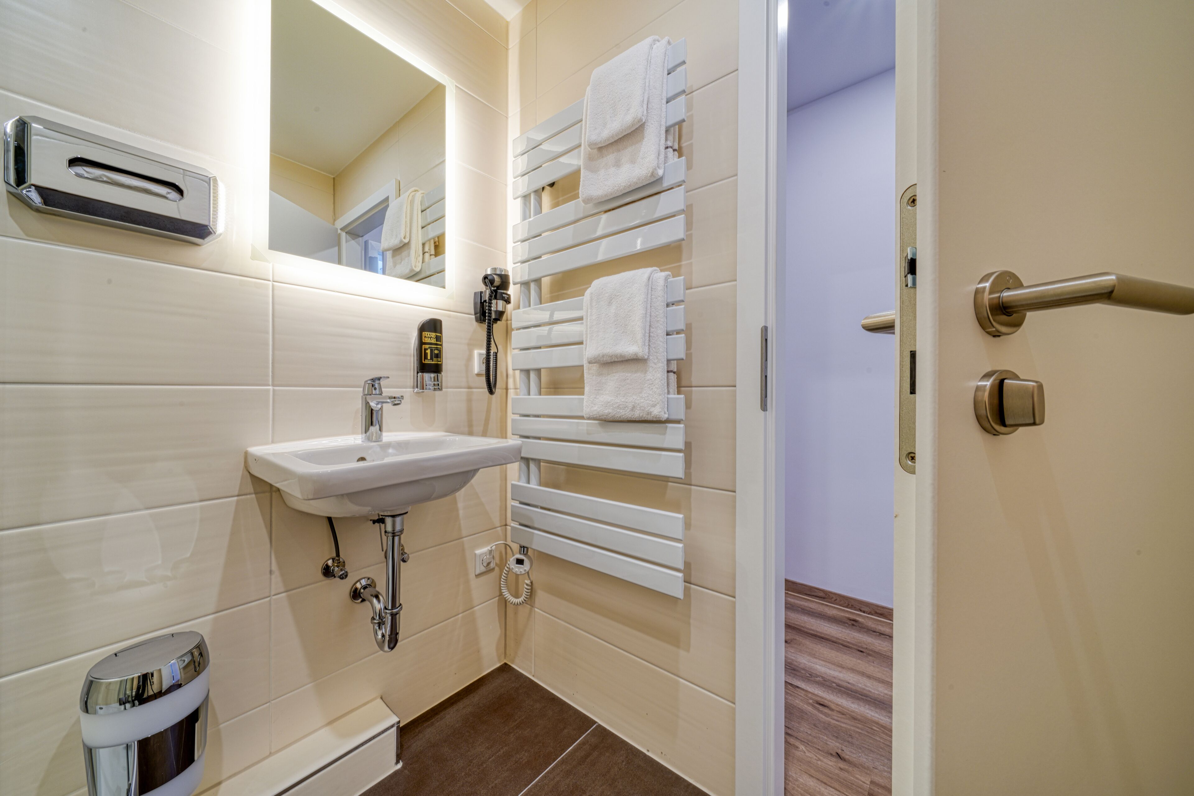 A bathroom with a sink, mirror, towel rack, and a toilet.