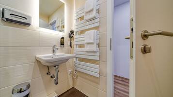 A bathroom with a sink, mirror, towel rack, and a toilet.