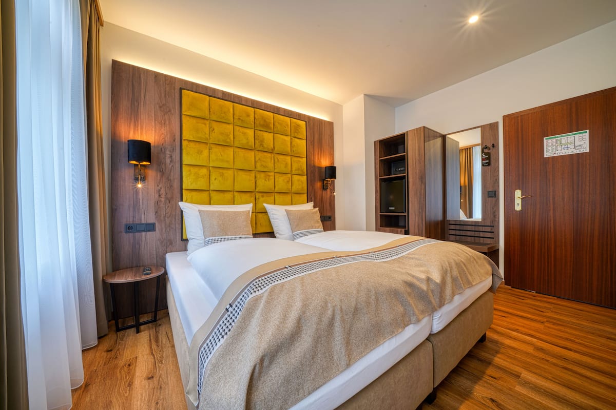 Una habitación de hotel moderna con una cama grande, cabecera de madera y armario empotrado.