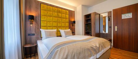 Una habitación de hotel moderna con una cama grande, cabecera de madera y armario empotrado.
