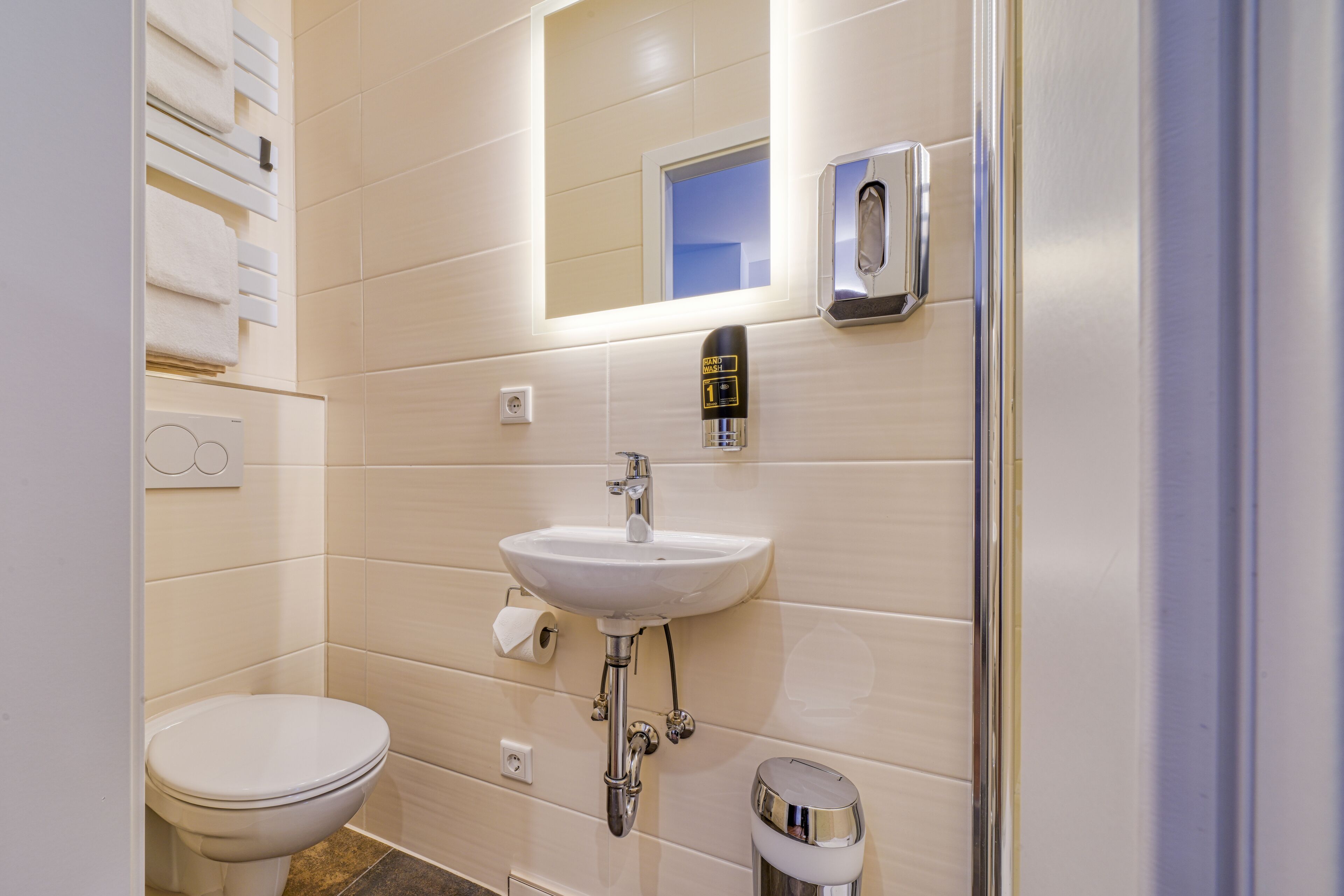 Een moderne badkamer met een wit toilet, een wastafel en een spiegel.