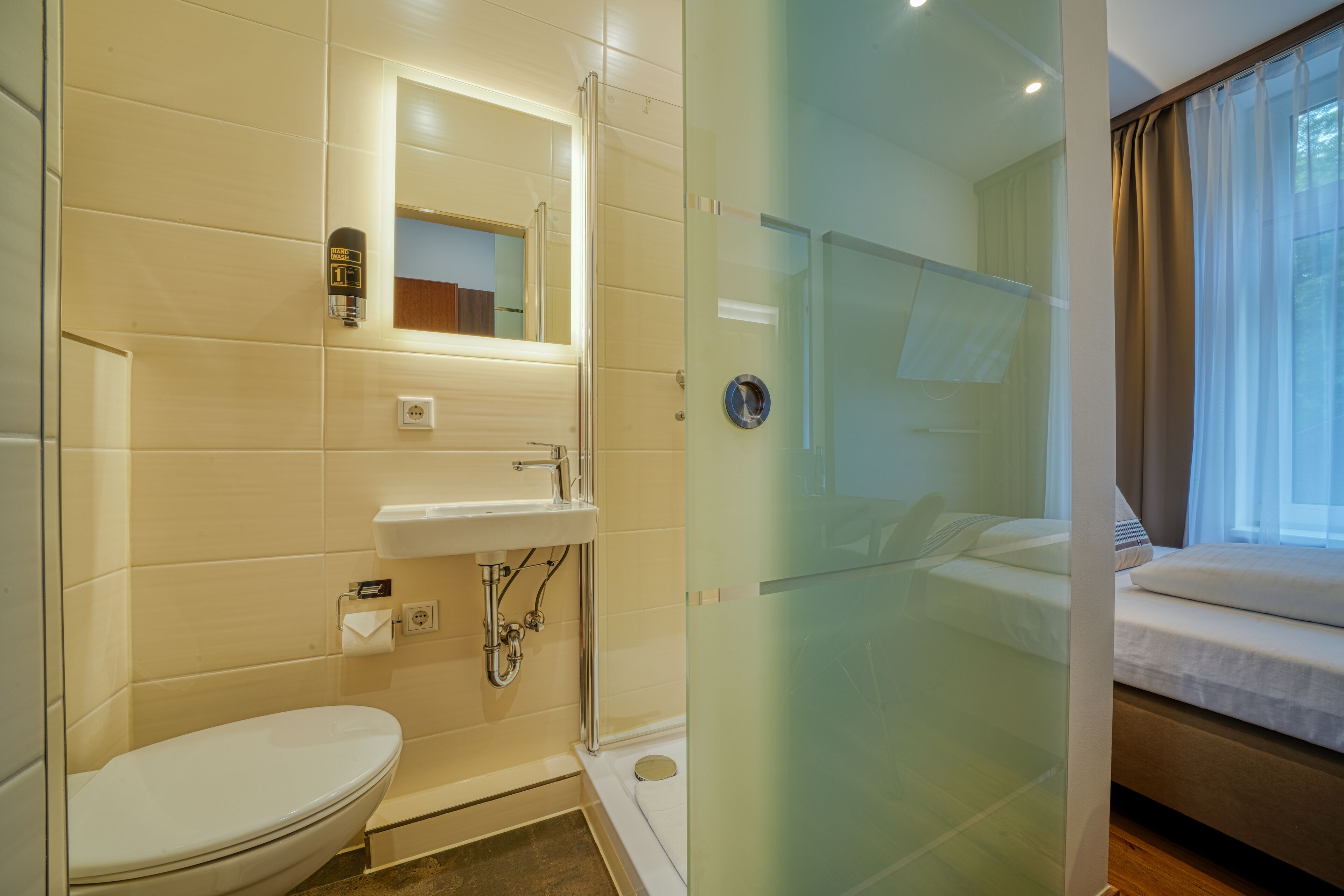 A modern bathroom with a toilet, sink, and glass shower enclosure.