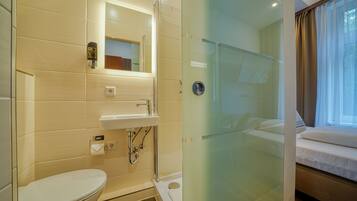 A modern bathroom with a toilet, sink, and glass shower enclosure.