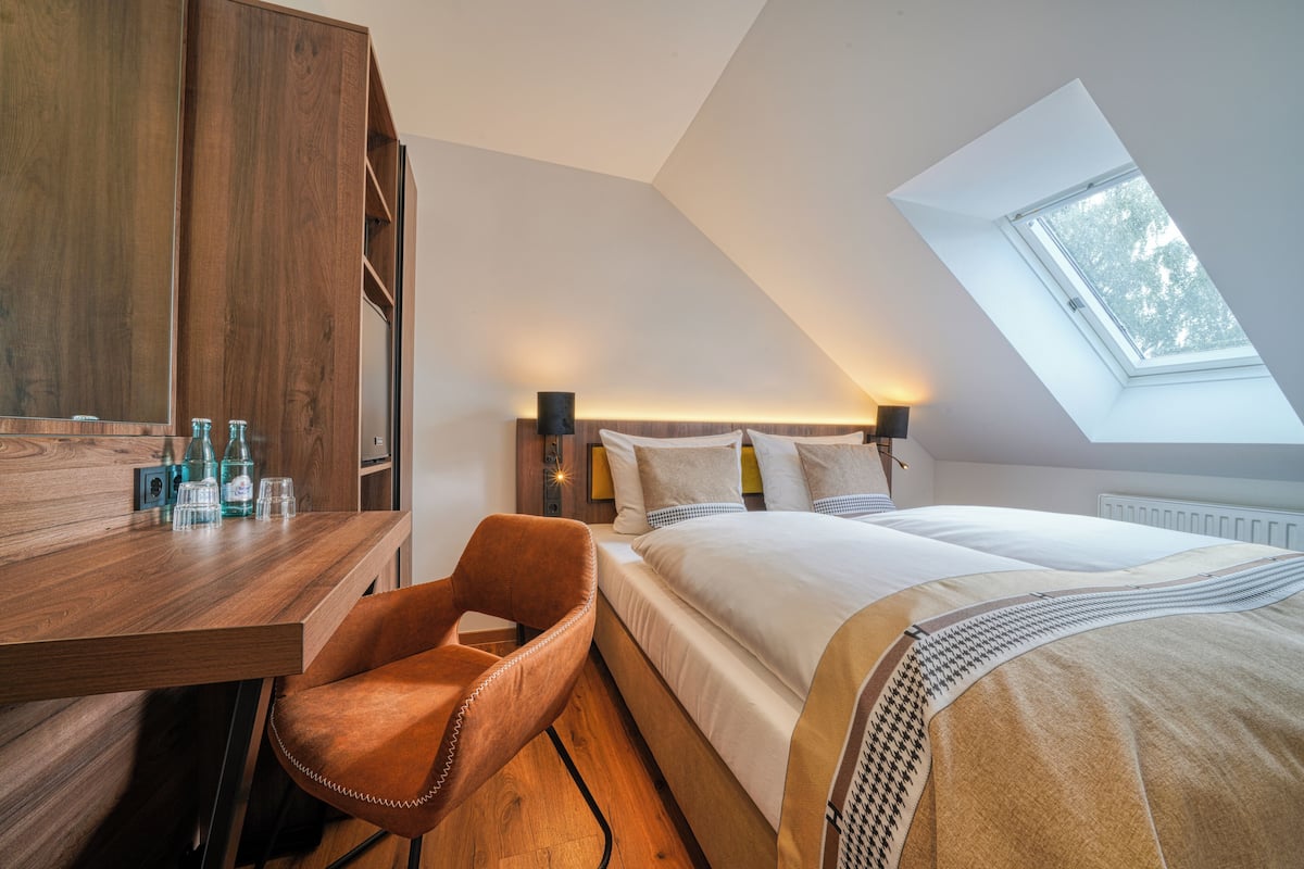 Un dormitorio con tragaluz, un escritorio de madera y una silla.