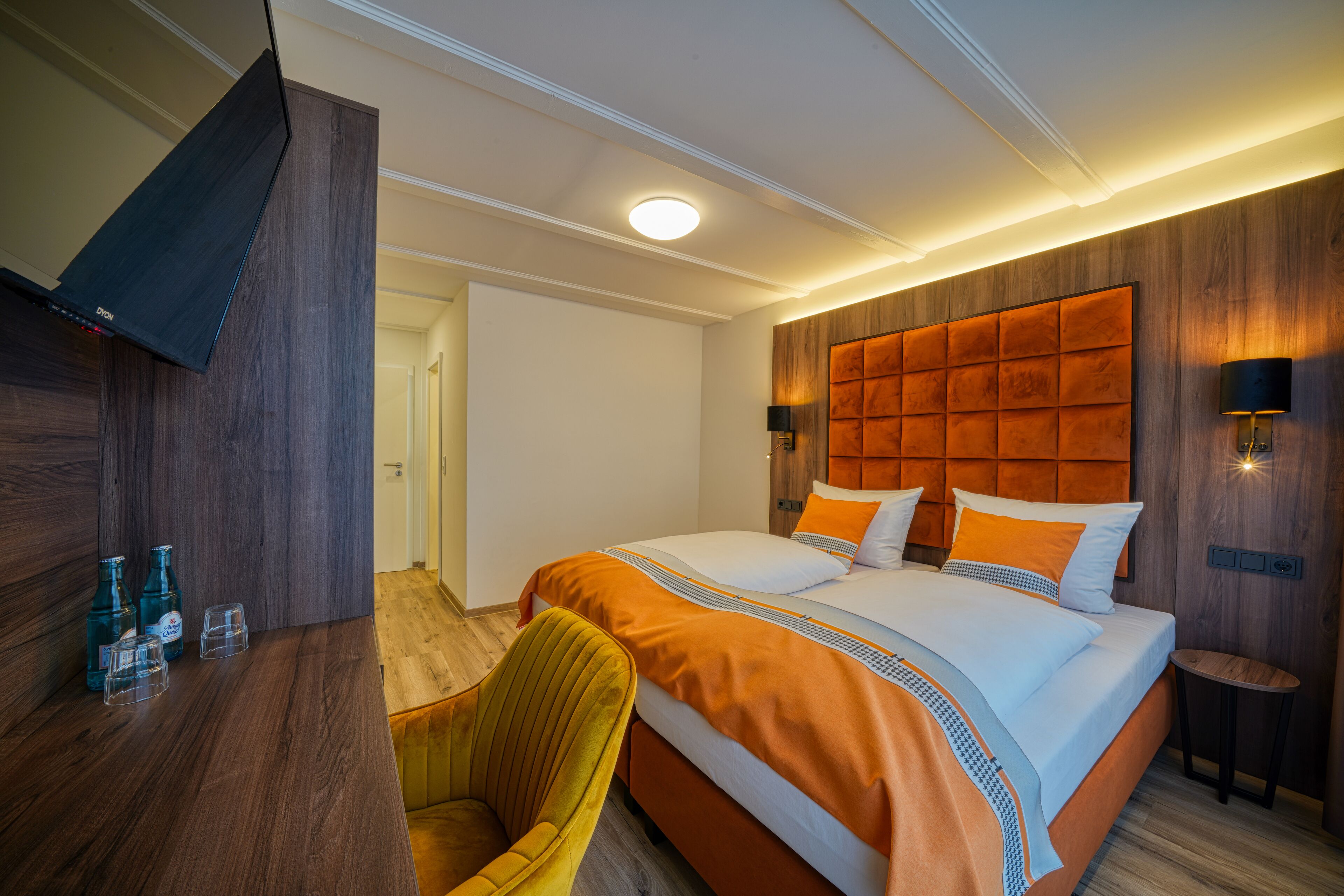 Una habitación de hotel con una cama grande, cabecera de madera y un escritorio con silla.