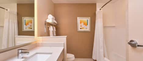 A modern bathroom with a large sink, toilet, and bathtub. There are two framed pictures on the wall.