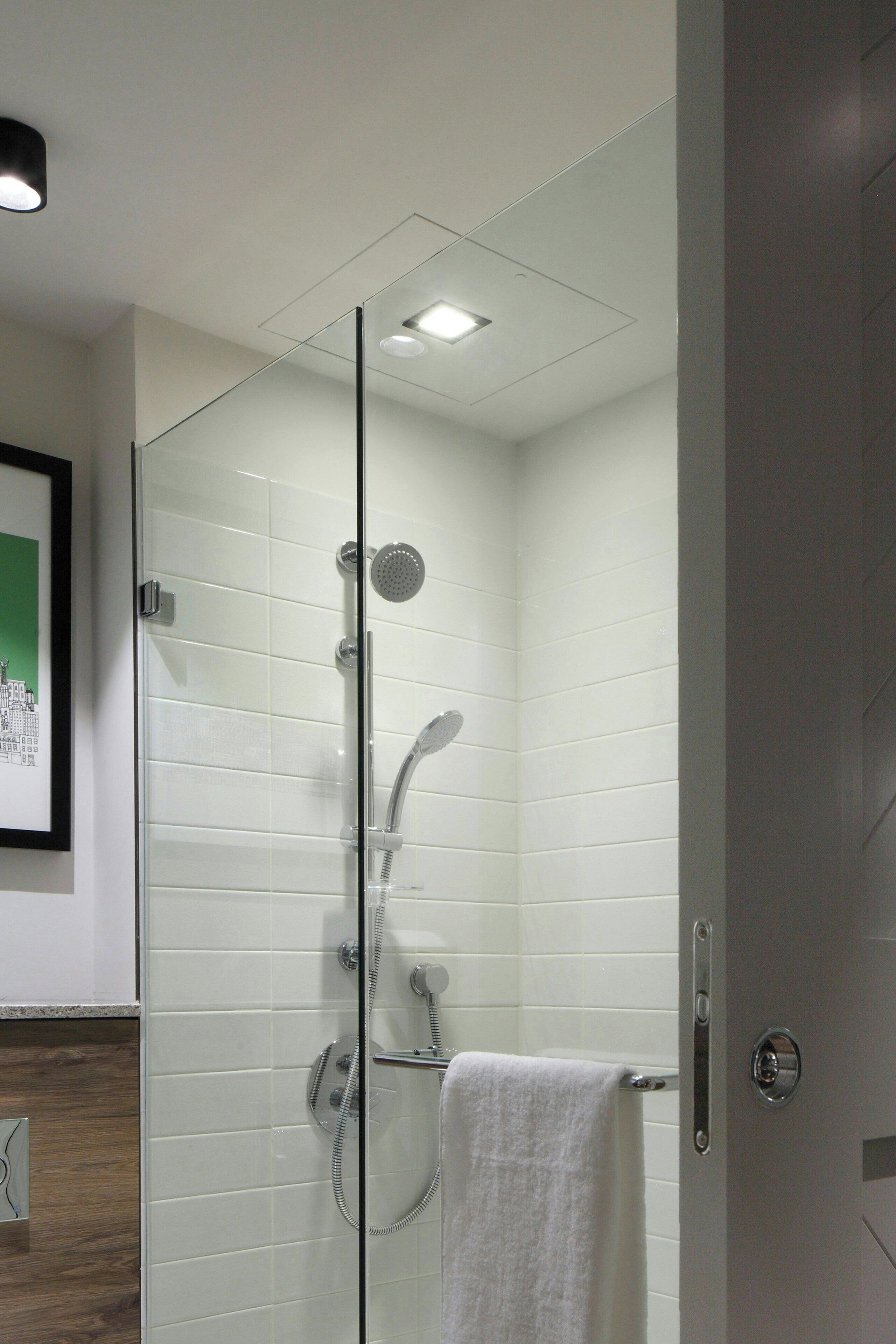 A glass-enclosed shower with a white towel hanging on the door handle.
