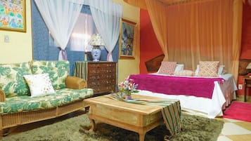 Quarto com cama, sofá, mesa de centro de madeira e cômoda.