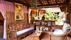 A cozy outdoor seating area with wicker furniture, a small table, and a variety of plants. - Pousada O Sole Mio (Planura)