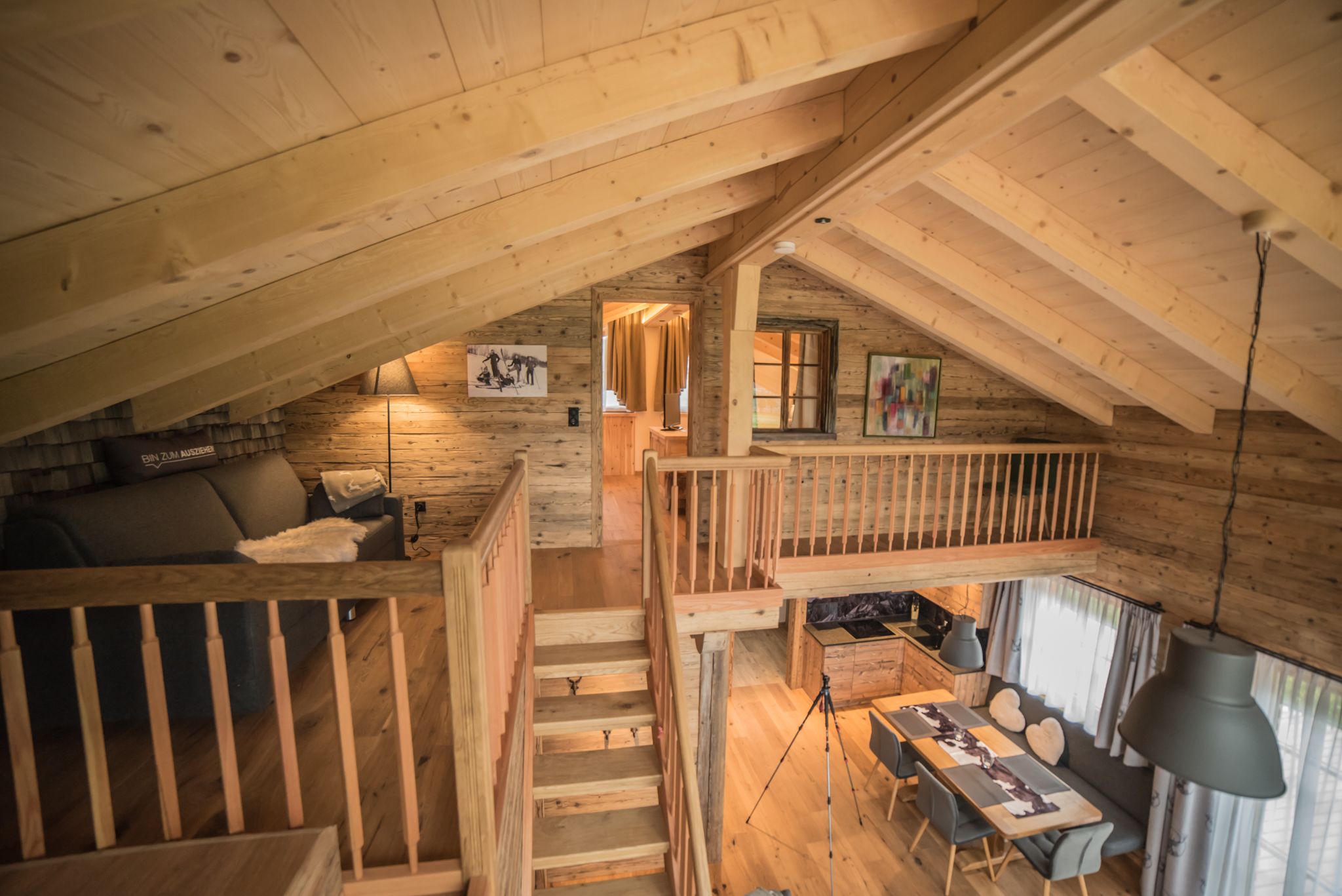 Un interior de madera con un dormitorio en entrepiso, un comedor y una escalera.