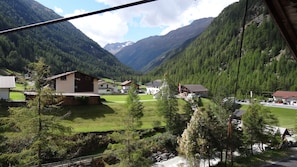 Un pueblo de montaña con casas, un arroyo pequeño y una carretera.