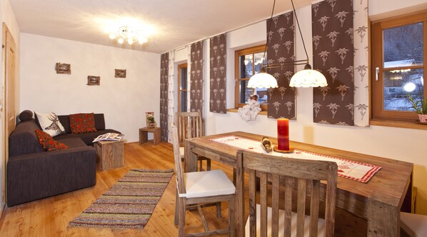 Una sala acogedora con un sofá, una mesa de comedor de madera y una alfombra.
