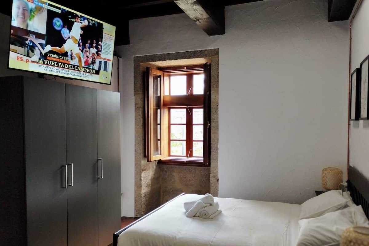 Un dormitorio con cama, armario y ventana.