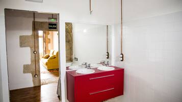 Un baño con tocador rojo, dos lavamanos y un espejo.