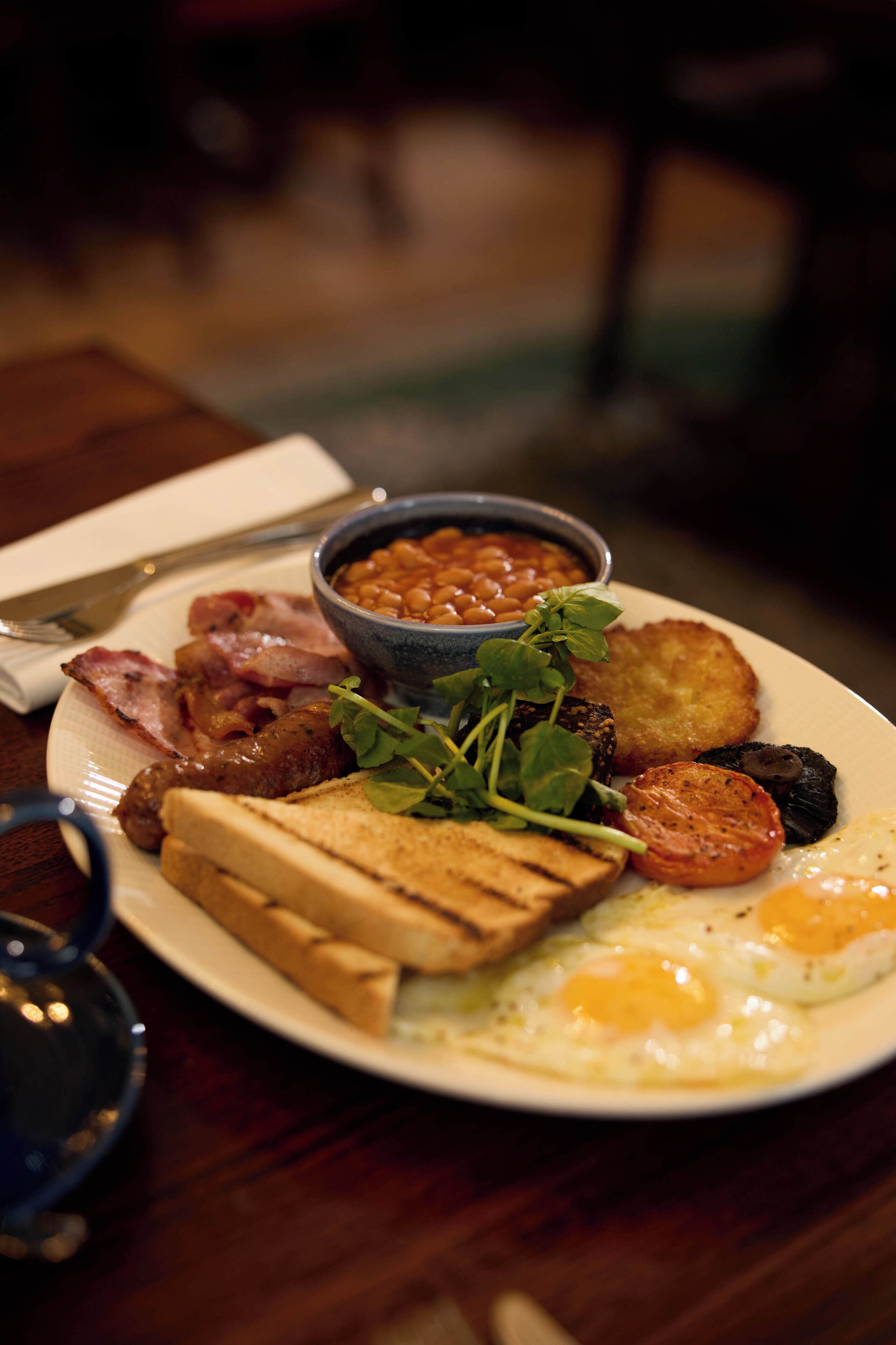 Une assiette de nourriture comprenant des haricots, du bacon, des œufs et des toasts.