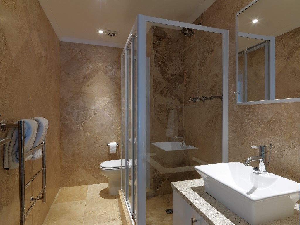 A modern bathroom with a glass-enclosed shower, a standalone sink, and a toilet.