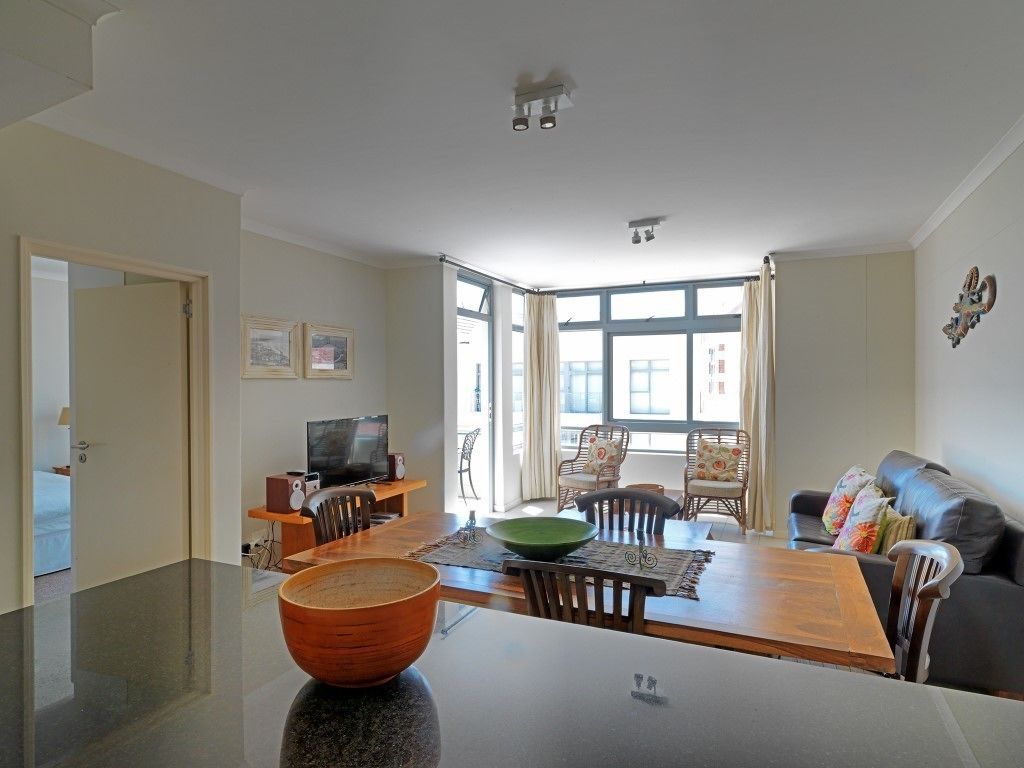 Una sala de estar moderna con comedor, ventanas amplias y un televisor de pantalla plana.