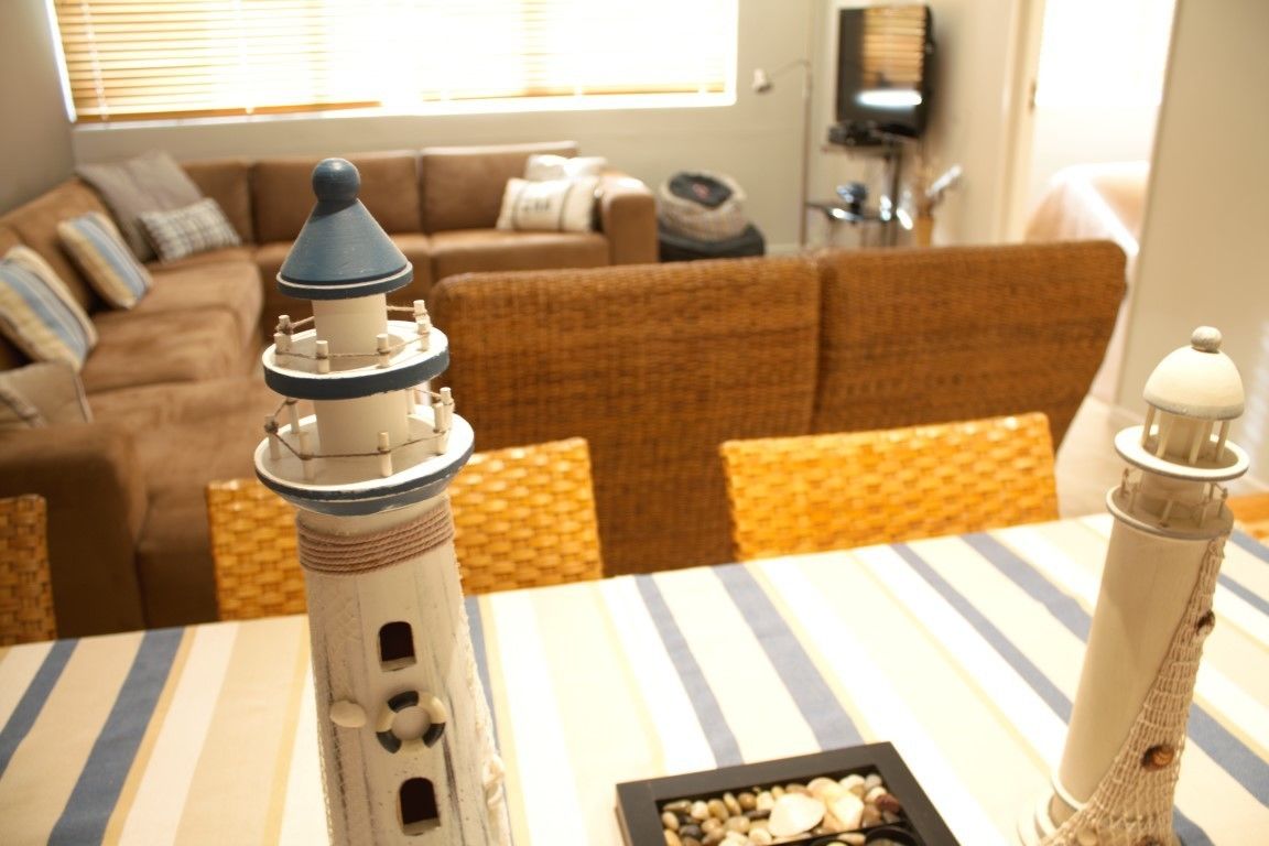 A living room with a striped tablecloth, a model lighthouse, and a wicker sofa.