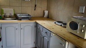 A kitchen with a wooden countertop, a microwave, a dishwasher, and a sink.