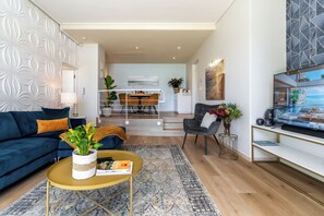 A modern living room with a blue sofa, a coffee table, and a TV stand.