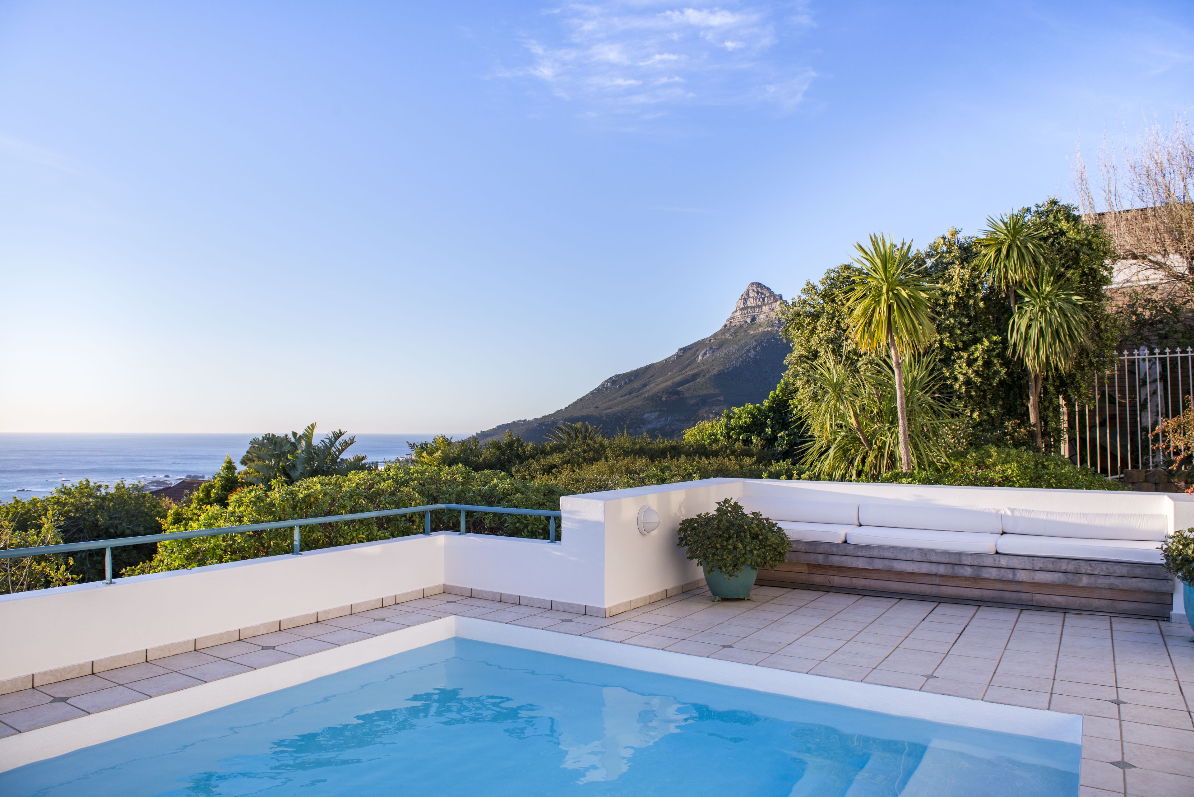 A rooftop pool with a view of the ocean and a mountain.