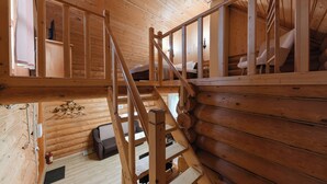 L’intérieur d’une cabane en bois comprend une chambre à coucher située en mezzanine, un escalier et un coin salon confortable.