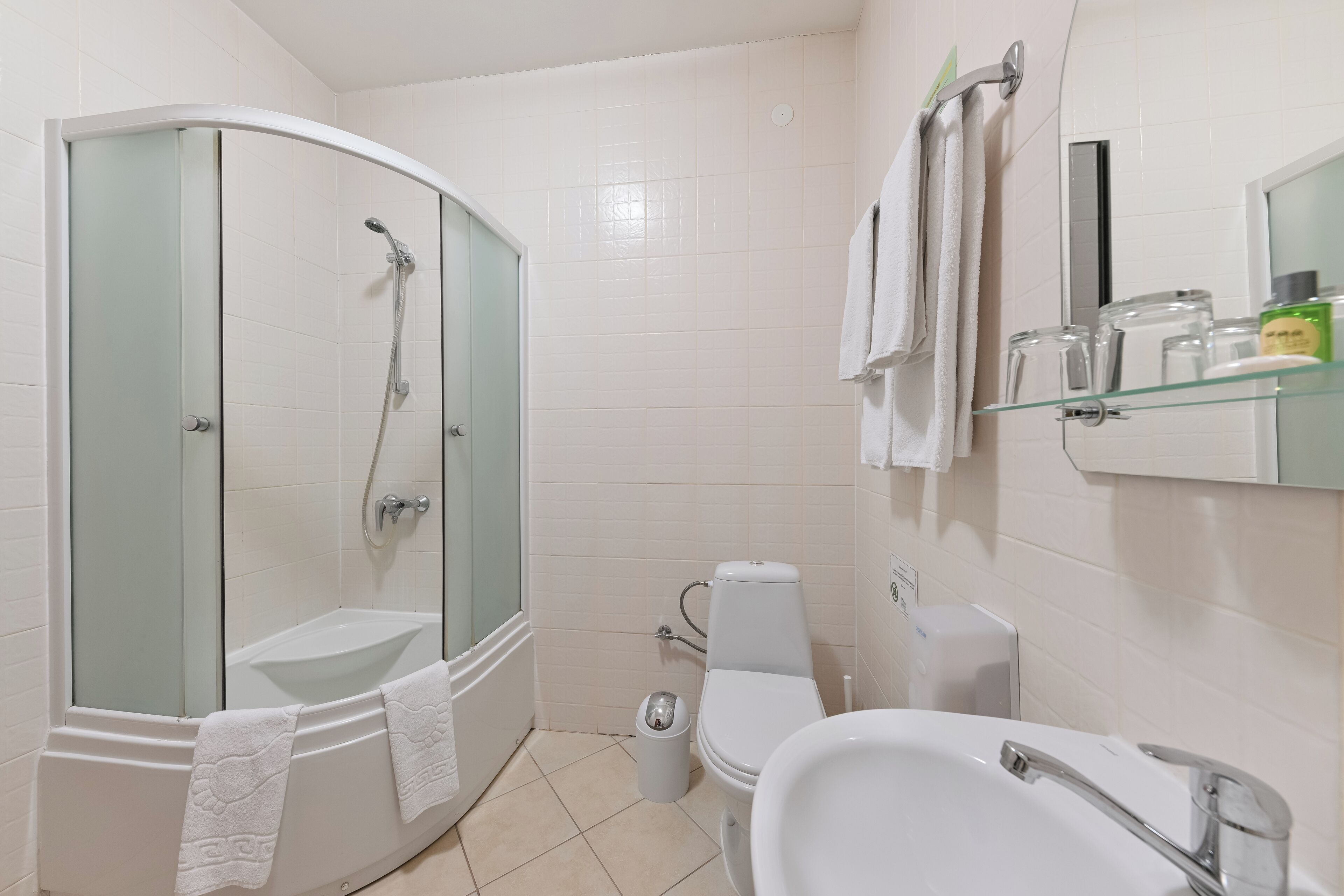 A modern bathroom with a glass-enclosed shower, a white sink, and a toilet.