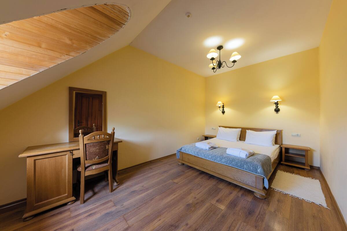 Un dormitorio con un escritorio de madera, una cama con colcha azul y dos lámparas de pared.