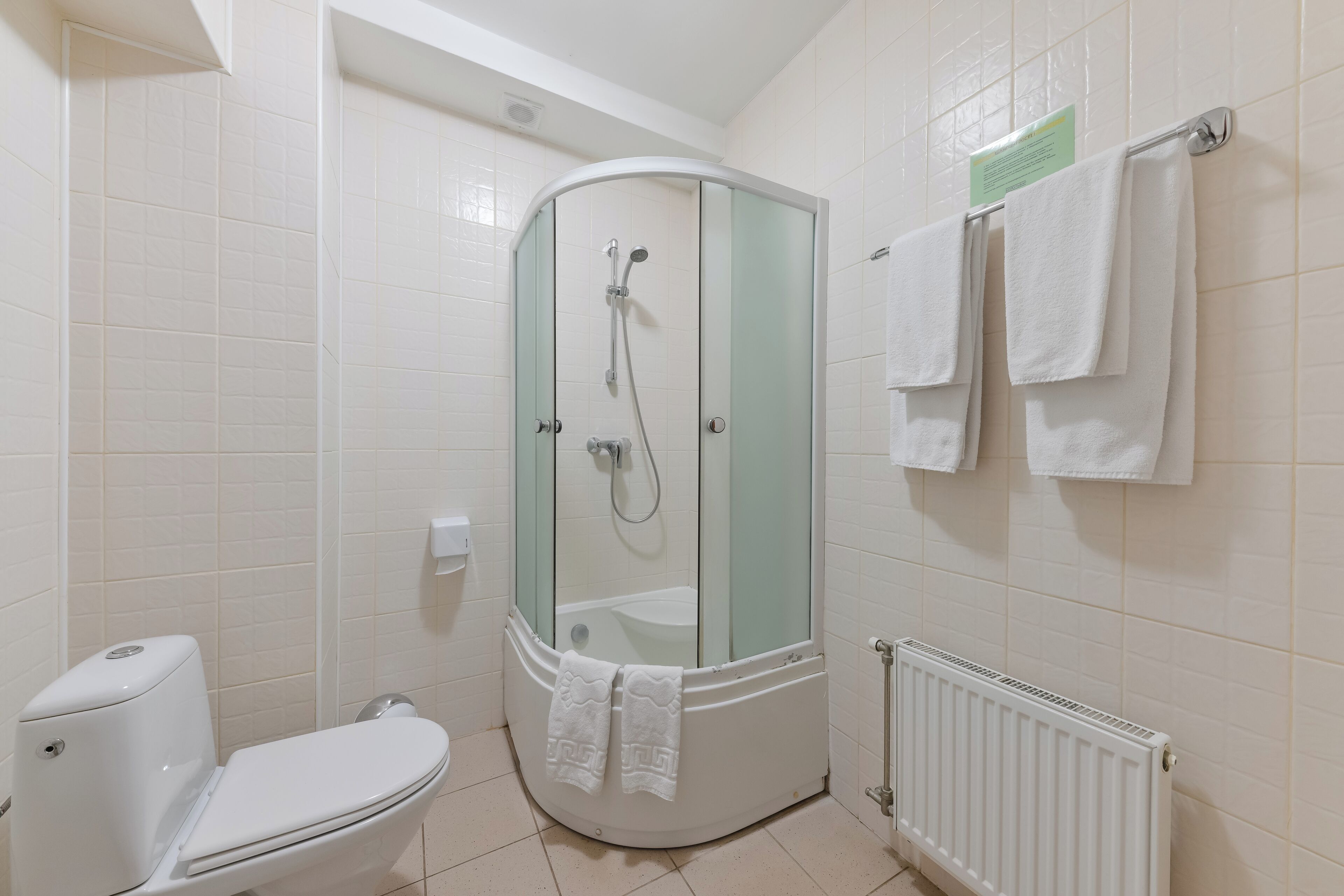 A bathroom with a glass-enclosed shower, a toilet, and a towel rack with towels.
