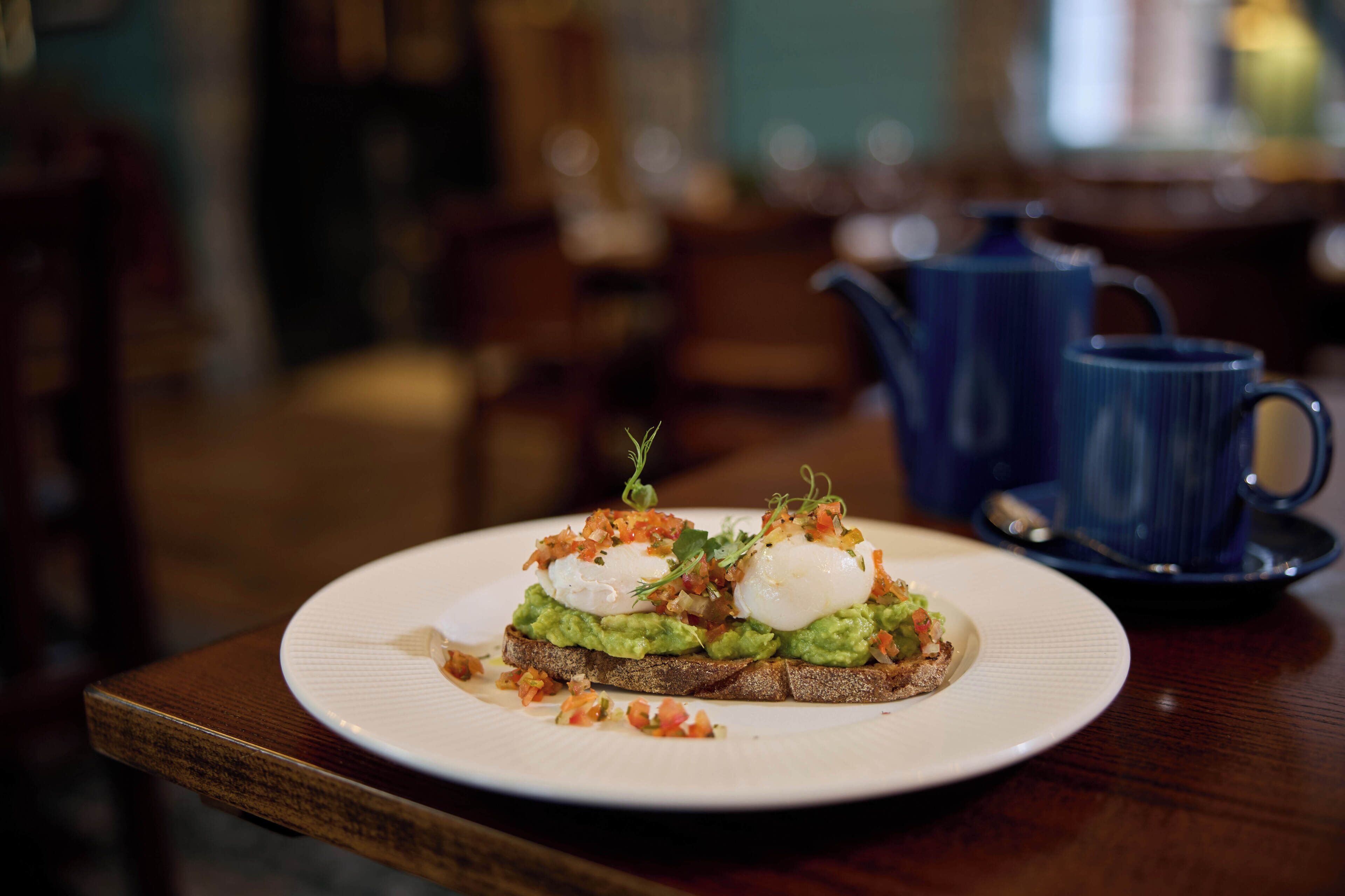 A plate of food on a wooden table with a blue teapot in the background.