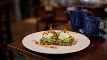 A plate of food on a wooden table with a blue teapot in the background.
