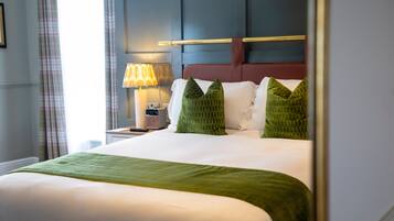 A neatly made bed with a green throw, a bedside lamp, and a headboard with a horizontal bar.