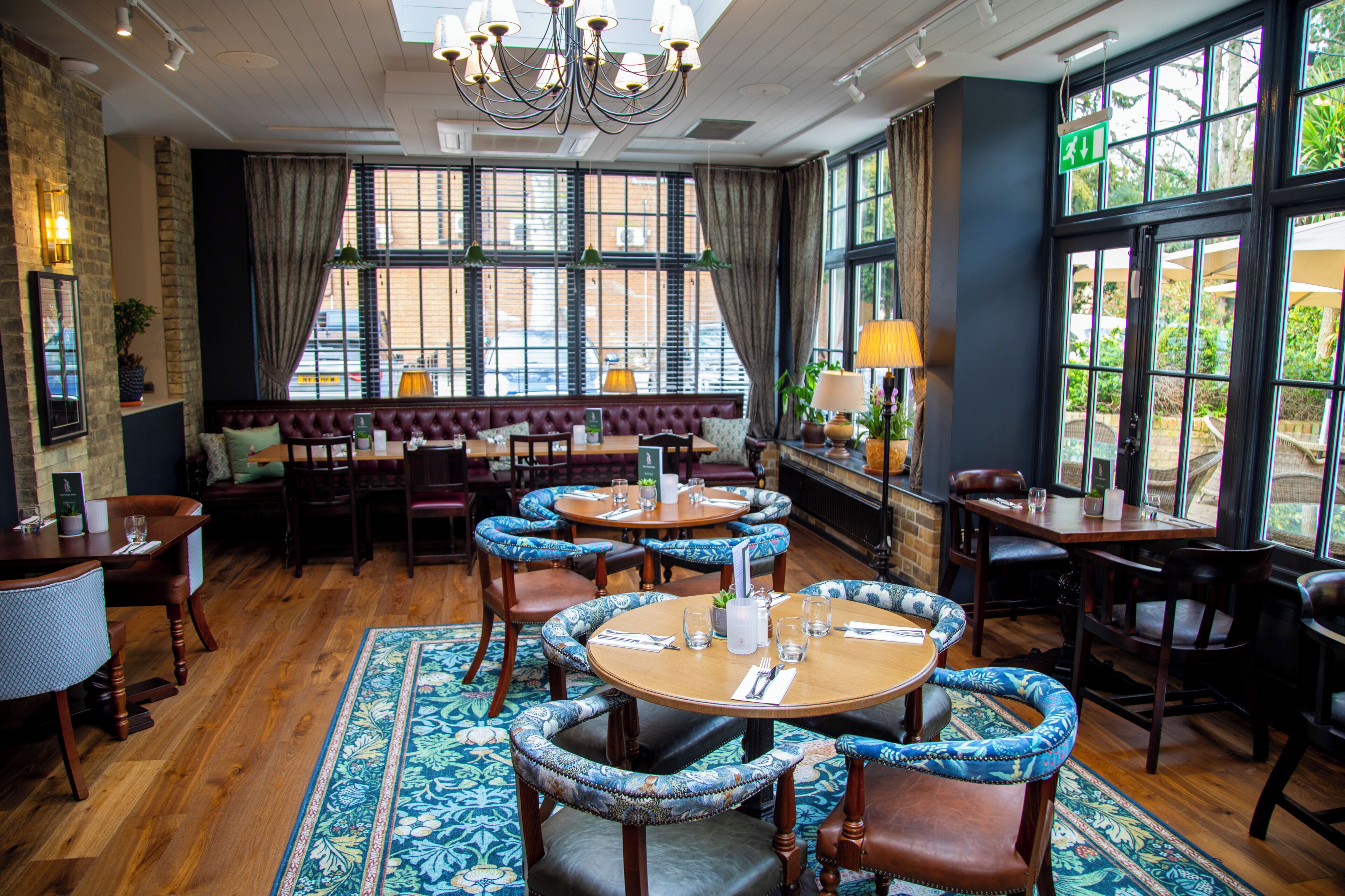 A restaurant with round tables, cushioned chairs, and a large window with a view.