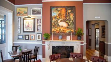A dining room with a fireplace, framed artwork, and a table set for four.