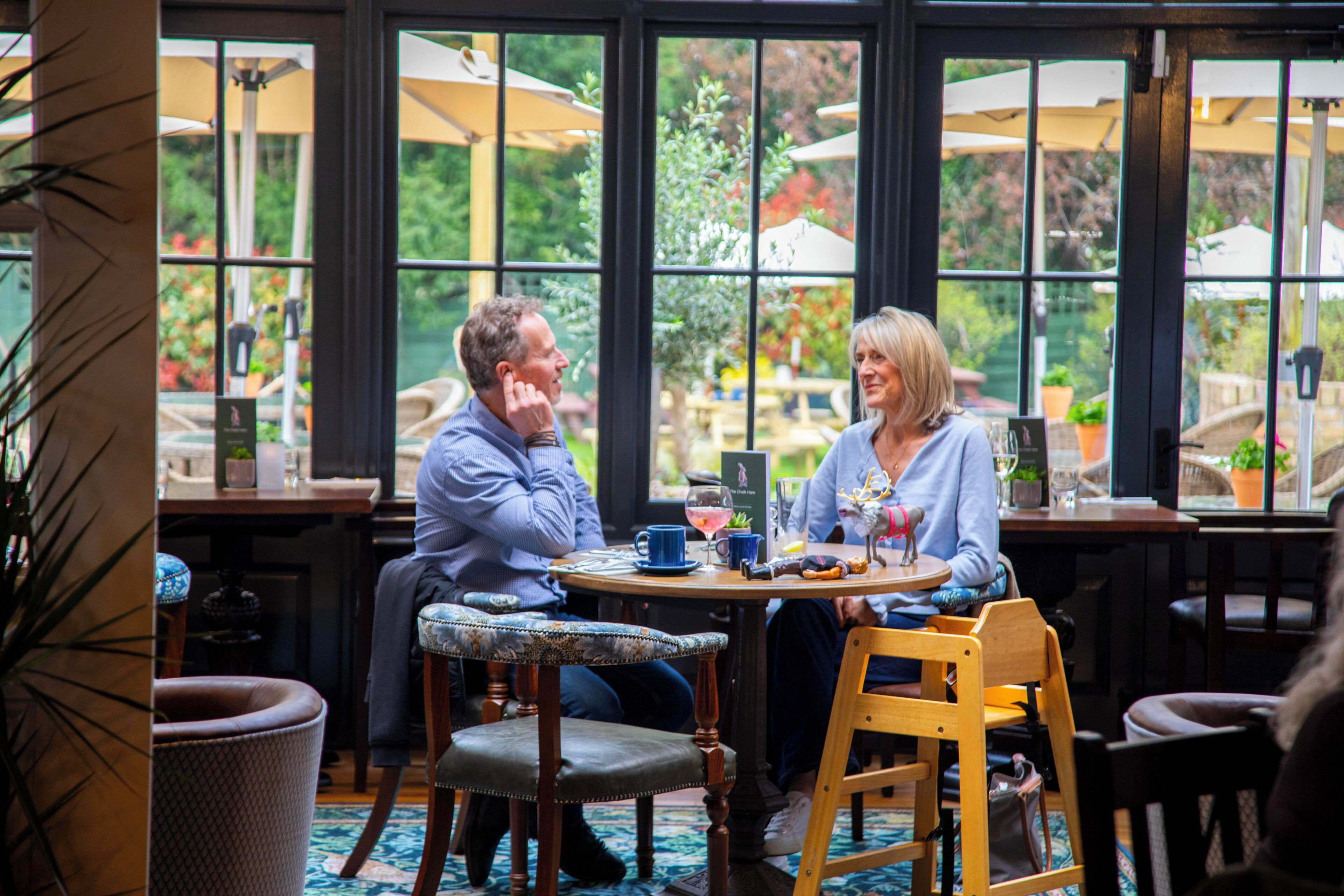 A couple seated at a round table with a view of greenery outside.