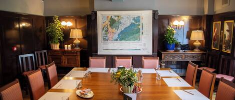 Une salle de conférence équipée d’une longue table, de chaises, d’un écran de projection et d’une carte.