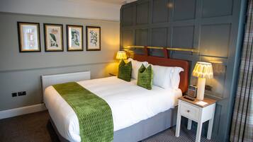 A hotel room with a bed, bedside lamps, a nightstand, and framed artwork on the wall.