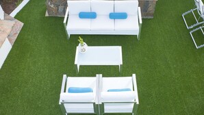 A patio with a white outdoor sofa set, a white coffee table, and a stone accent wall. - Be Cool Resort - Adults Only (San Bartolomé de Tirajana)