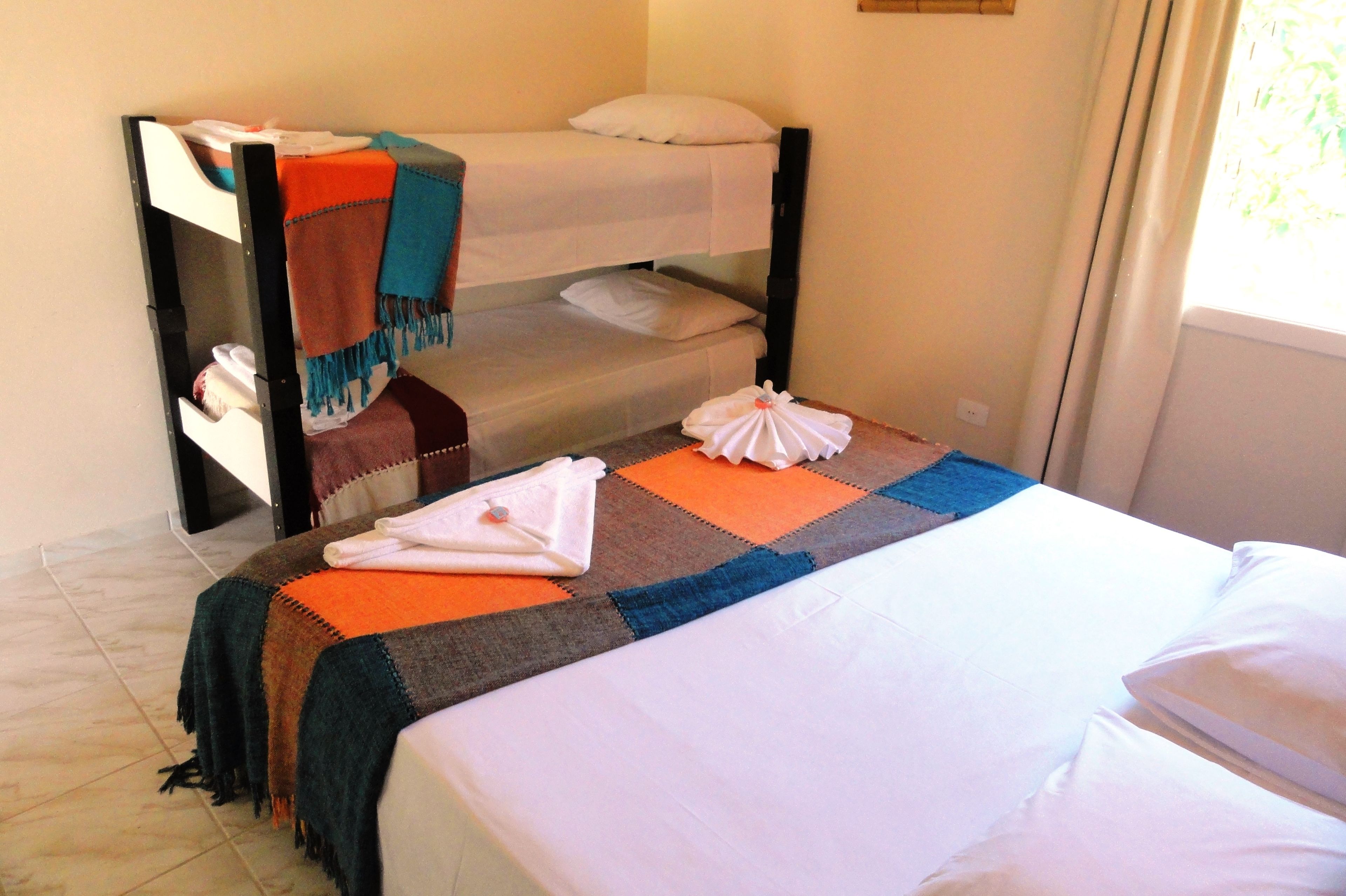 Een hotelkamer met een stapelbed, een eenpersoonsbed en een kleurrijke quilt.
